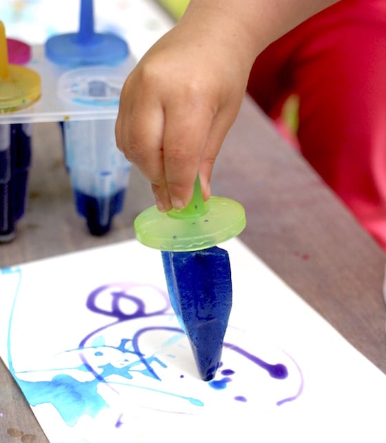 child painting with blue ice pop