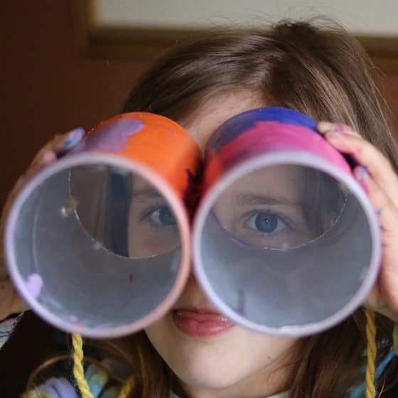 child looking through binoculars she made with pringles cans