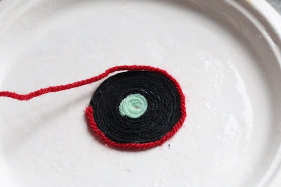 black and red yarn wound in circles on paper plate