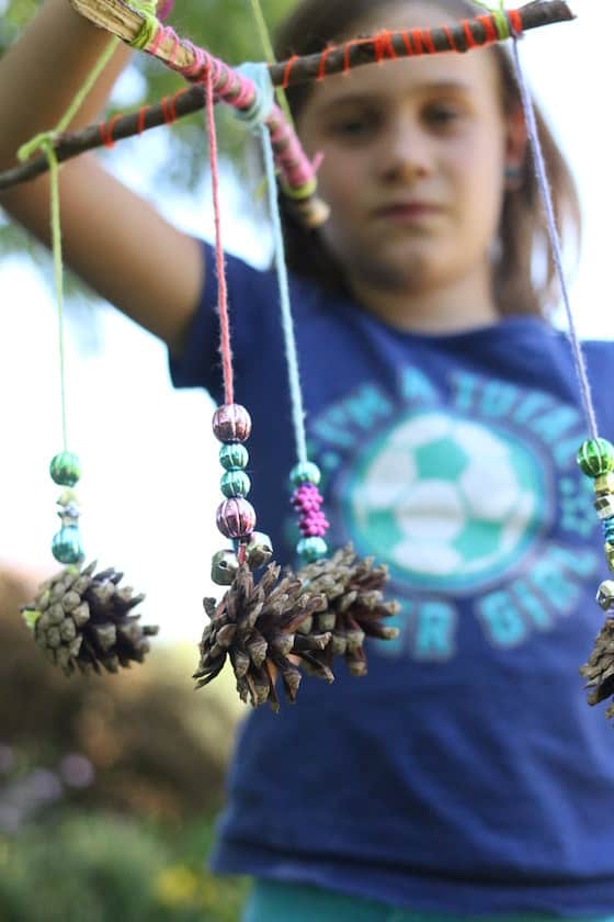 child holding homemade pinecone mobile