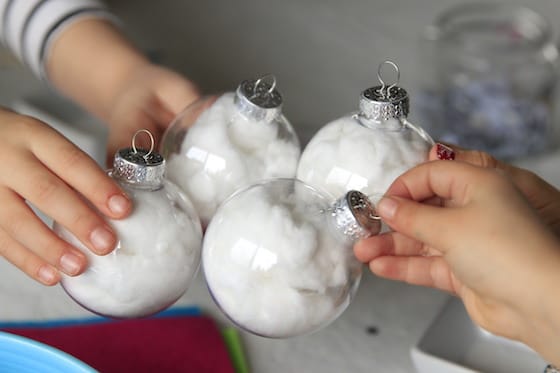 Kids holding clear plastic baubles stuffed with cotton balls