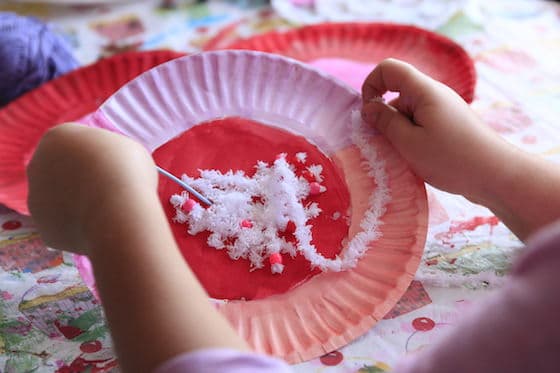 child sewing with white yarn