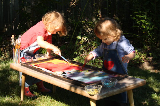 preschooler and toddler painting mirror outside