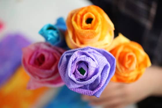 Child holding purple, pink, blue and yellow paper towel roses