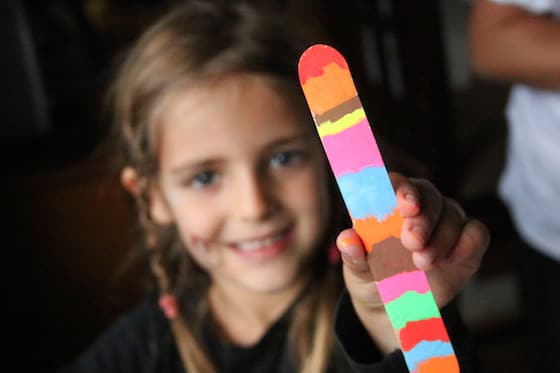 Child holding craft stick bookmark