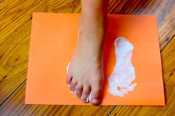 Child making print on paper with foot