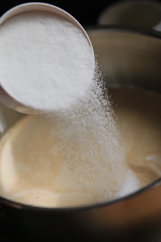 pouring sugar into creme brulee recipe