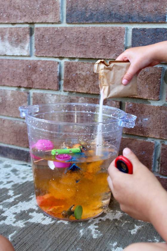 preschooler adding colour to bucket of water