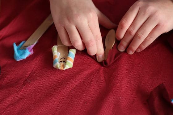 child wrapping popsicle stick in fabric