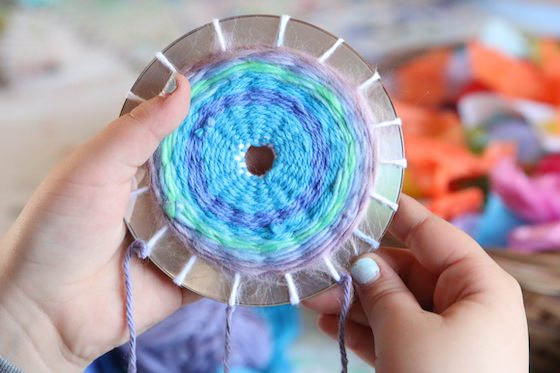 Child holding CD woven with yarn