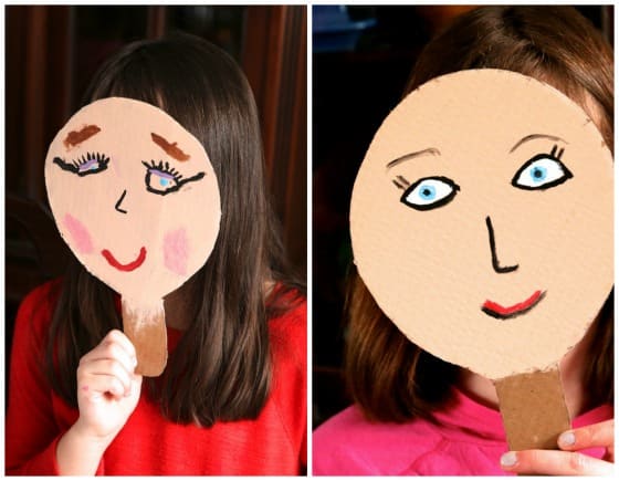 Kids holding homemade puppet paddles up to their faces