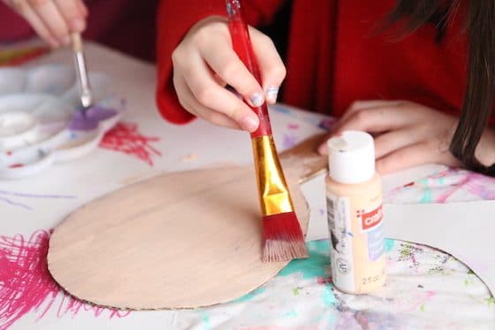 Child painting base coat on cardboard puppet