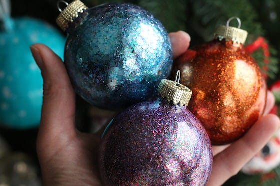hand holding copper, blue and purple glittered ornaments