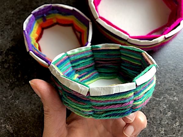 folding edges of paper plate down over weaving