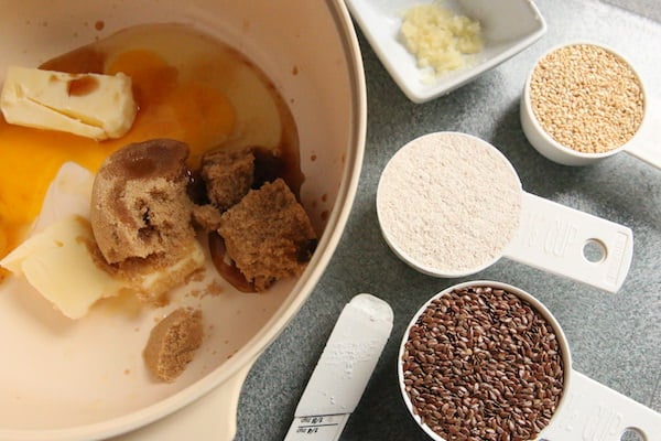 butter sugar egg in bowl, flax seeds, sesame seeds, ginger beside bowl