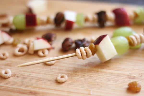 threading cereal and fruit on skewer