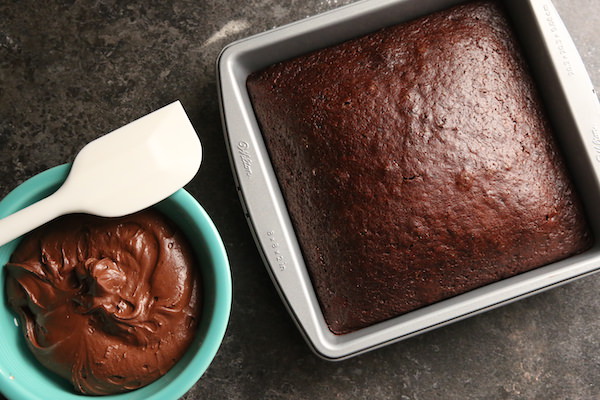 Chocolate cake in pan with bowl of chocolate frosting