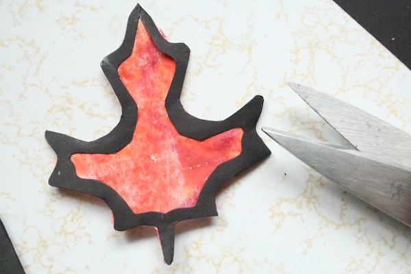 black paper maple leaf silhouette glued to painted wax paper