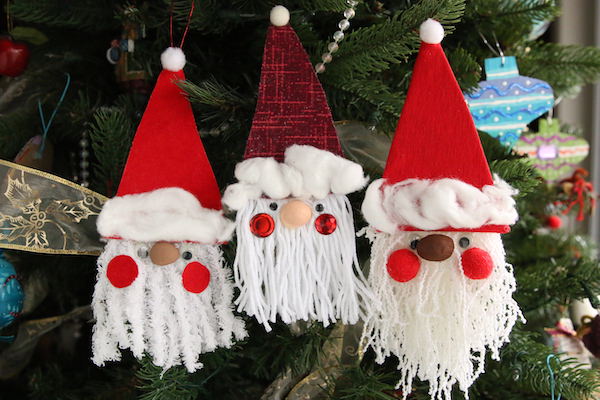 3 yarn and cardboard santas hung horizontally on Christmas tree