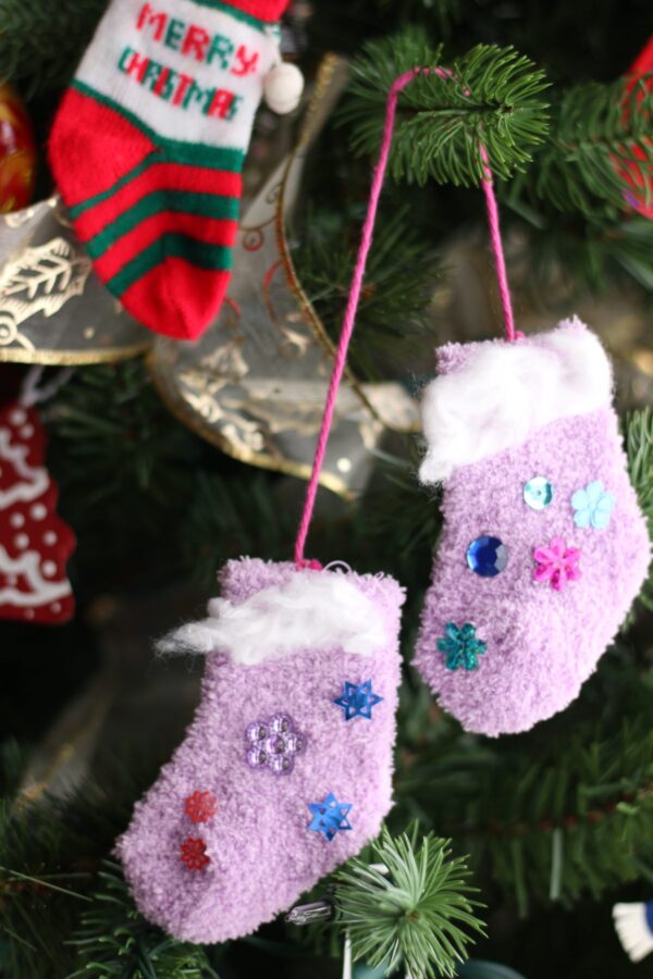 2 purple baby socks and 1 red baby sock hung on Christmas tree as mini stockings