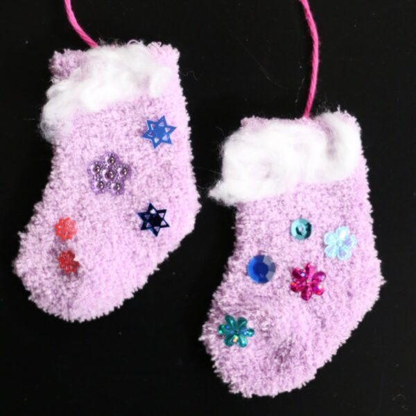 baby socks decorated with white time and sequins, strung together on black background