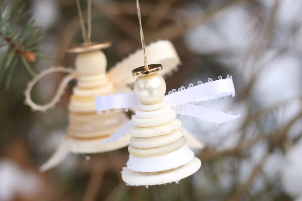 cream and white button angel ornaments with snowy backdrop